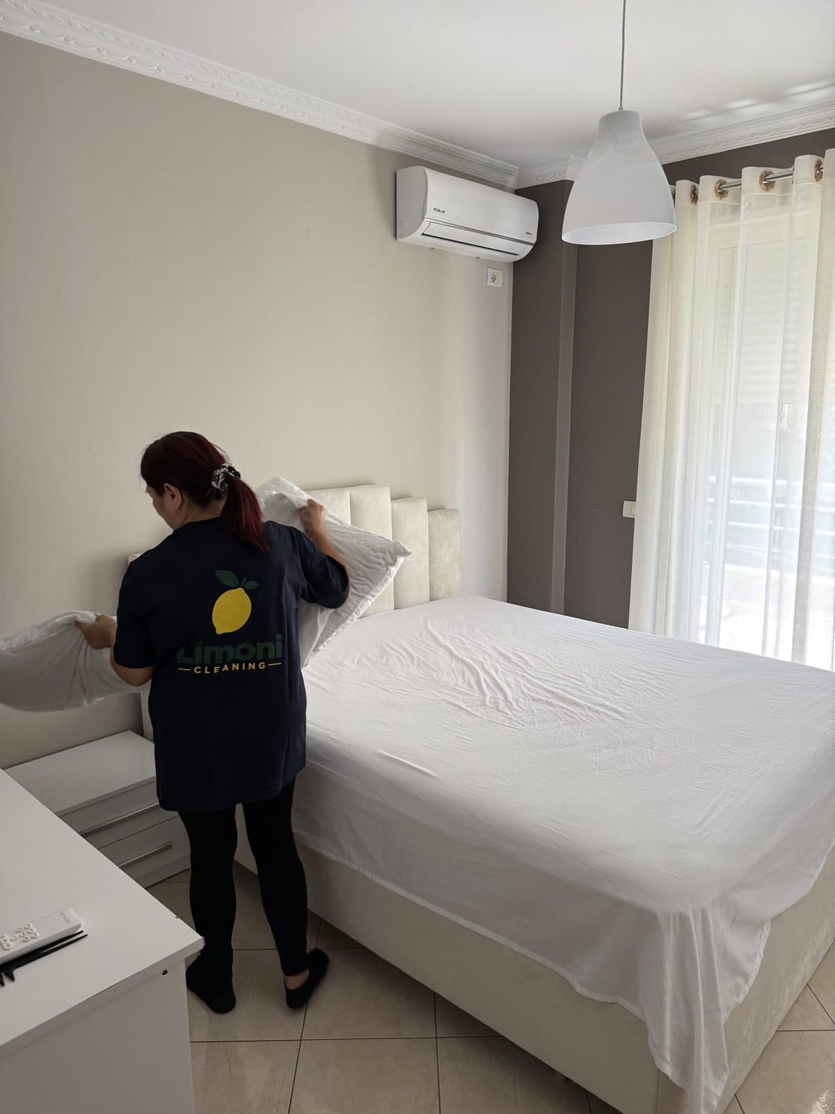 Punonjëse e Limoni Cleaning duke rregulluar shtratin në një dhomë gjumi në Tiranë